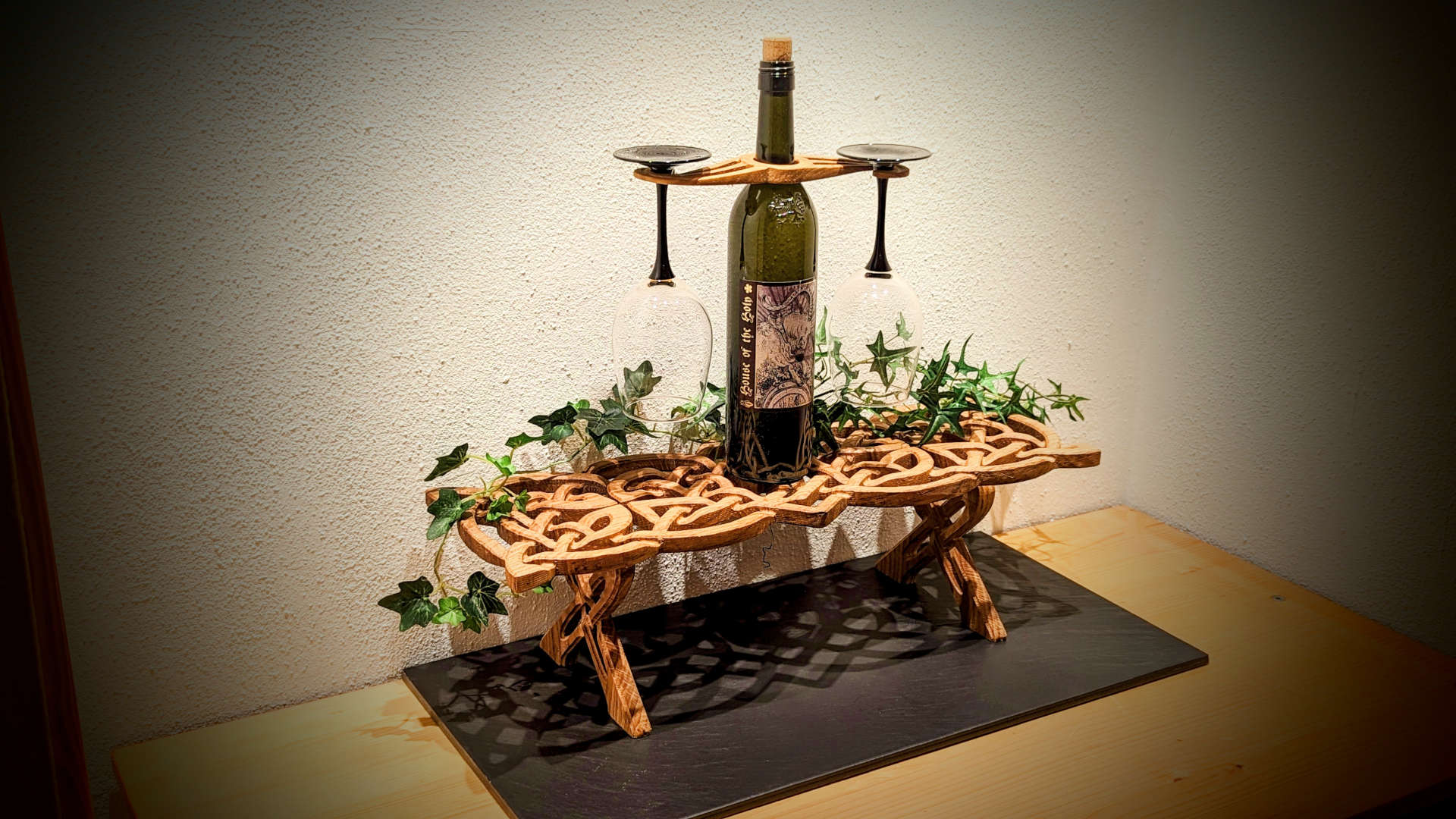 An oak table centrepiece carved in Celtic style with a wine bottle on top.