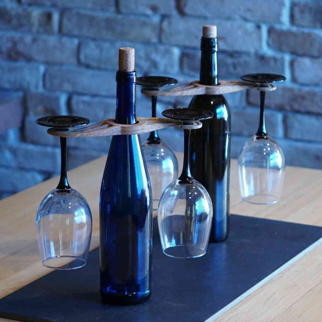 Two wine bottles, each with a holder made of oak wood with two wine glasses suspended in it.